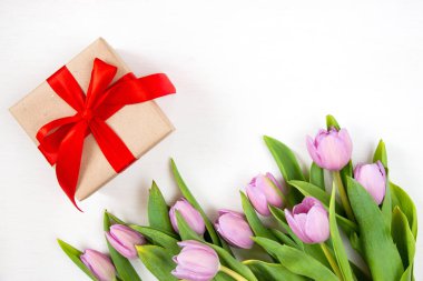 Beyaz arka planda laleler ve hediye kutusu. Temiz metin alanı olan şenlikli çiçek konsepti. Düz yatıyordu. Yukarıdan görüntüle.