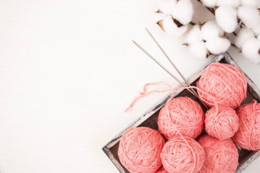 Pembe iplik derileri, metalik örgü iğneleri ve hafif arka planda bir pamuk dalı. Kadın nakış işi konsepti. Düz yatıyordu.