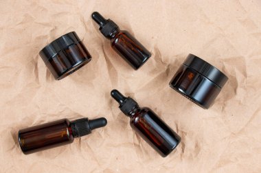 Buruşmuş el işi kağıdının üzerindeki kehribar camından yapılmış komik şişeler. Cilt bakım ürünleri ambalaj tasarımı. Spa konsepti.