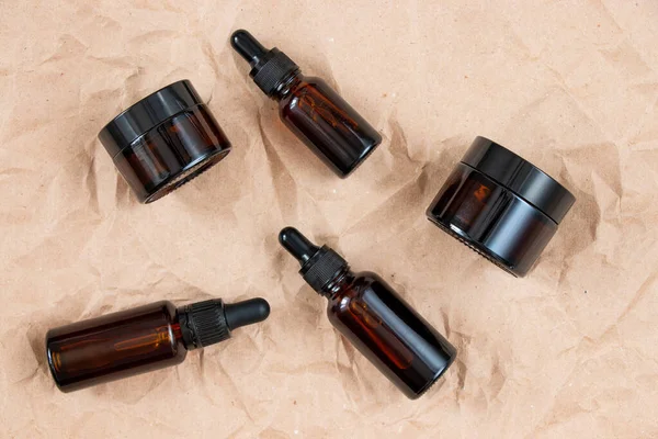 Buruşmuş el işi kağıdının üzerindeki kehribar camından yapılmış komik şişeler. Cilt bakım ürünleri ambalaj tasarımı. Spa konsepti.