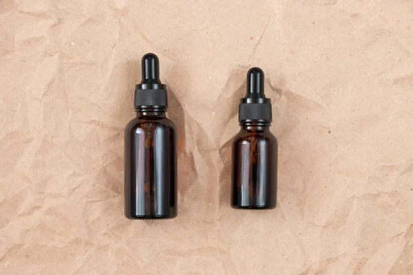 Buruşmuş el işi kağıdının üzerindeki kehribar camından yapılmış komik şişeler. Cilt bakım ürünleri ambalaj tasarımı. Spa konsepti.