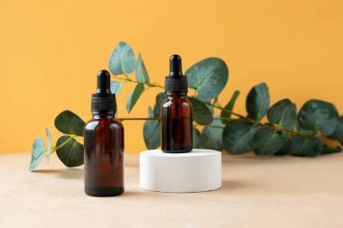 Kehribar cam damlatıcısı olan bir kozmetik şişesi beton bir kaidede oturur. Doğal güzellik ürünleri. Mineral organik yağ. Cilt bakımı için boş şişe. Sert güneş ışığı.