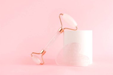 Beton bir podyumda yüz masajı için gül kuvars silindiri. Güzellik ve cilt bakımı konsepti. Yaşlanma karşıtı terapi ve kaldırma.