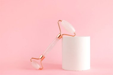 Beton bir podyumda yüz masajı için gül kuvars silindiri. Güzellik ve cilt bakımı konsepti. Yaşlanma karşıtı terapi ve kaldırma.