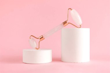 Beton bir podyumda yüz masajı için gül kuvars silindiri. Güzellik ve cilt bakımı konsepti. Yaşlanma karşıtı terapi ve kaldırma.