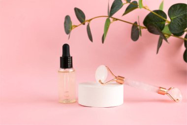 Yüz masajı için pembe kuvars silindiri ve pembe arka planda bir kavanoz kozmetik serumu. Güzellik ve cilt bakımı konsepti. Yaşlanma karşıtı terapi ve kaldırma.