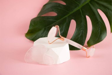 Beton bir podyumda yüz masajı için gül kuvars silindiri. Güzellik ve cilt bakımı konsepti. Yaşlanma karşıtı terapi ve kaldırma.