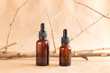 Komik kehribar cam şişeler ve pastel arka planda kuru ahşap dallar. Cilt bakım ürünleri ambalaj tasarımı. Spa konsepti.