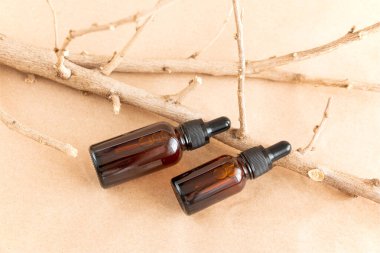 Komik kehribar cam şişeler ve pastel arka planda kuru ahşap dallar. Cilt bakım ürünleri ambalaj tasarımı. Spa konsepti.