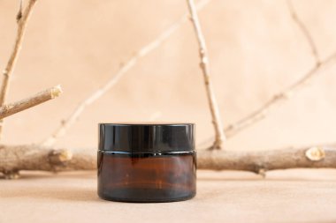 Krema için komik cam kavanoz ve pastel arka planda kuru ahşap dallar. Cilt bakım ürünleri ambalaj tasarımı. Spa konsepti.