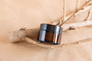 Krema için komik cam kavanoz ve pastel arka planda kuru ahşap dallar. Cilt bakım ürünleri ambalaj tasarımı. Spa konsepti.