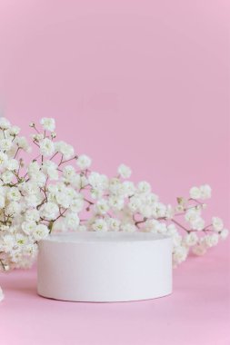 Pembe arka planda betondan yapılmış boş bir podyum. Çingenenin çiçek açan dalı. Doğal kozmetik ve berning konsepti.