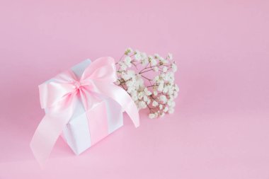 Hediye kutusu ve pembe arka planda bir buket çiçek açan çingene çiçeği. Anneler Günü tatili konsepti. Boşluğu kopyala.