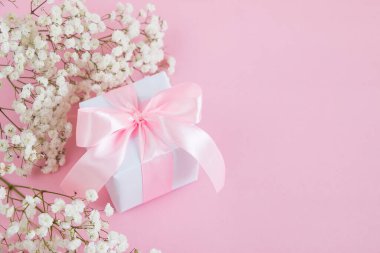 Hediye kutusu ve pembe arka planda bir buket çiçek açan çingene çiçeği. Anneler Günü tatili konsepti. Boşluğu kopyala.