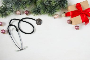 Noel 'i sağlık hizmetlerinde kutluyoruz. Düz manzaralı. Stetoskop, beyaz arka planda süsleri olan köknar dalları. Üst manzara, düz uzanma.