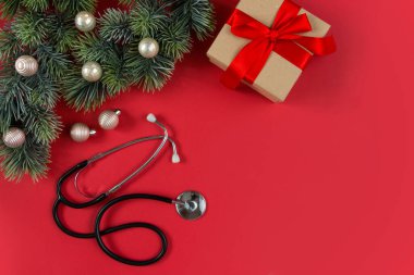 Noel 'i sağlık hizmetlerinde kutluyoruz. Düz manzaralı. Stetoskop, beyaz arka planda süsleri olan köknar dalları. Üst manzara, düz uzanma.