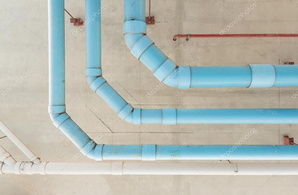 Pipas de agua colgando en el techo de cemento del edificio — Fotos de