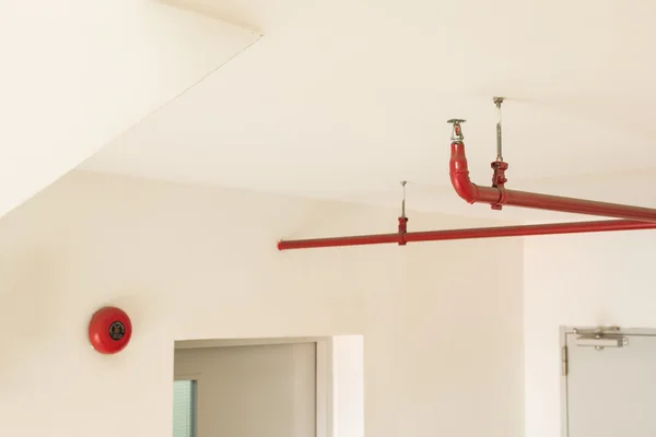 Fire sprinkler and red pipe hanging on ceiling of buliding — Stock Photo, Image