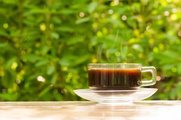 Szkło kubek czarnej kawy na drewnianym stole — Zdjęcie stockowe