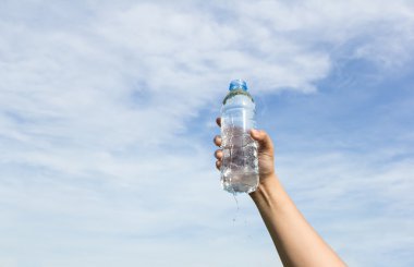 hand holding water bottle on cloud and sky clipart