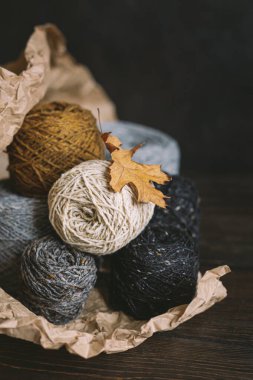 Koyu bir arka planda kuru meşe yaprağıyla el örmek için iplik yumakları. El yapımı ve yavaş ev hayatı için sonbahar arka planı. Seçici odak.