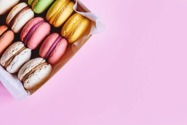 Bir kutu içinde lezzetli Fransız badem kurabiyeleri. Pembe pastel arka plan. Metin için yer.