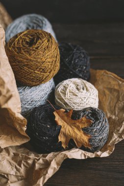 Koyu bir arka planda kuru meşe yaprağıyla el örmek için iplik yumakları. El yapımı ve yavaş ev hayatı için sonbahar arka planı. Seçici odak.