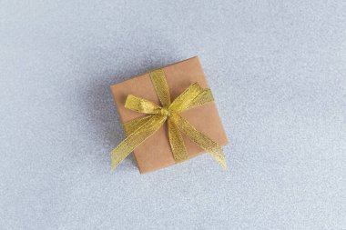 Gri parlak arka planda altın kurdeleli hediye kutusu. Mesaj için yer. Düz yatıyordu.