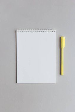 Boş sayfalı ve gri arkaplanlı sarı kalemli bir defter. Düz yatıyordu. Metin için yer. 