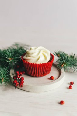 Beyaz arka planda ladin dalları ve kırmızı böğürtlenlerle süslenmiş lezzetli bir kek. Noel kutlaması için şekerler. Tatil çevre dostu kavram. Metin için yer.