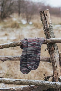 Eski ahşap bir çite bir çift çok renkli el örgüsü çorap. Doğal renkler. Kırsal arkaplan. 