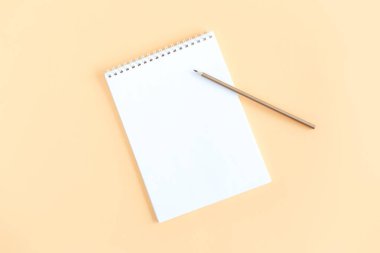 Şeftali rengi arka planda boş sayfa ve kalem olan defter. Düz yatıyordu. Metin için yer. 