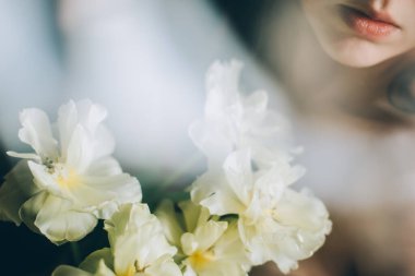 Yumuşak beyaz şakayık laleler ve gün ışığında genç ve güzel bir kız. Bahar konsepti Seçici odak.