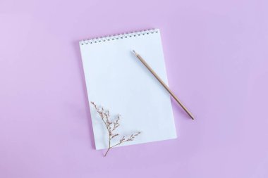 Menekşe rengi pastel arka planda boş sayfa ve kalem olan defter. Düz yatıyordu. Metin için yer. 