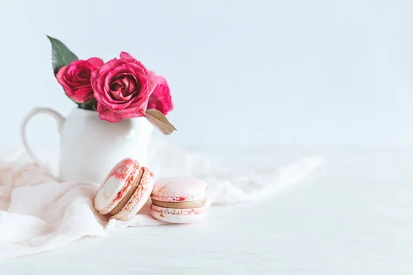 Tasty french macaroons with pink roses on a white background.  Place for text.