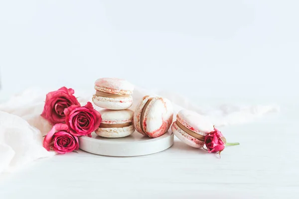 Lekkere Franse Macarons Met Roze Rozen Een Bord Witte Achtergrond — Stockfoto