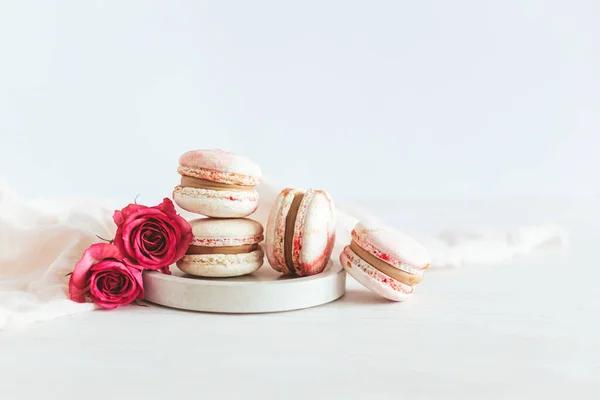 Lekkere Franse Macarons Met Roze Rozen Een Bord Witte Houten — Stockfoto