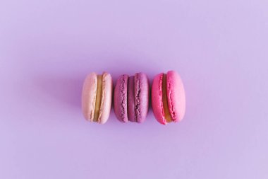 Menekşe pastel arka planda lezzetli Fransız badem kurabiyeleri. Pembe ve mor badem kurabiyeleri. Metin için yer.