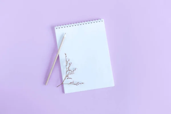 Menekşe rengi pastel arka planda boş sayfa ve kalem olan defter. Düz yatıyordu. Metin için yer. 
