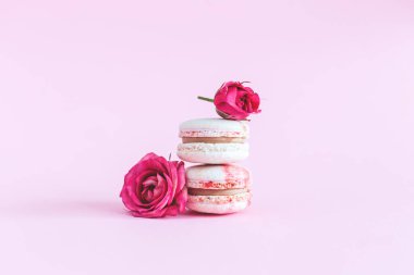 Pembe pastel arka planda yumuşak güllü lezzetli Fransız badem kurabiyeleri. Metin için yer.