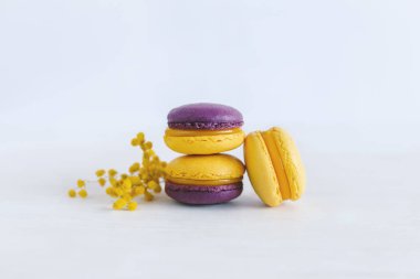 Beyaz ahşap arka planda çiçekli lezzetli Fransız kurabiyeleri. Mor ve sarı renkler. Metin için yer.