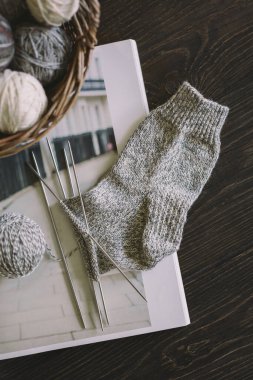 Koyu ahşap arka planda, iğneli el örgüsü çorabı ve iplik topları. El yapımı ve yavaş yaşam için higge kavramı.  
