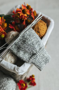 Koyu ahşap arka planda, iğneli el örgüsü çorabı ve iplik topları. El yapımı ve yavaş yaşam için higge kavramı.  