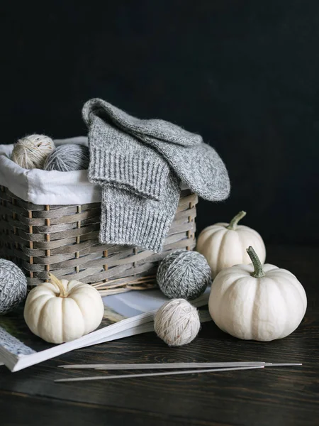 Şırıngalı el örgüsü çoraplar, iplik topları ve tahta arka planda balkabakları. El yapımı ve yavaş yaşam için higge kavramı.  