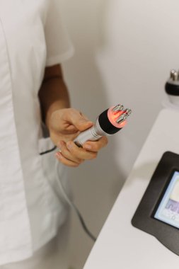 Kozmetik bilimci kozmetoloji kliniğinde RF kaldırma cihazı tutuyor. Kapatın. Kozmetoloji kavramı.