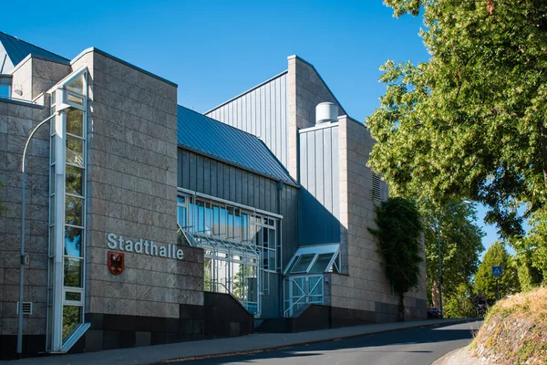 Stadthalle Wetzlar, Almanya 'nın Wetzlar kentindeki belediye binası ve kültür etkinliği mekanı. Çağdaş mimarisi, cam giriş cephesi ve açık mavi gökyüzü altında ağaçlarla dolu şehir caddesi olan modern şehir binası. Gün ışığı.