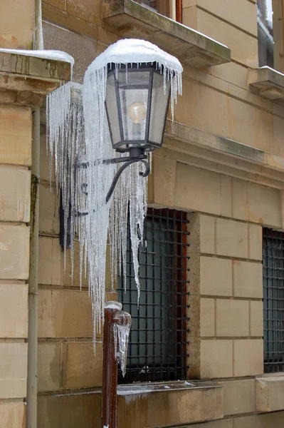 Sokak lambası, binanın ön cephesine sarkıtlarla kaplı. Soğuk kış koşulları, kentsel bir ortamda donmuş dokular ve potansiyel tehlikeler yaratır. Kış, hava, şehir yaşamı ve iklim kavramları için ideal