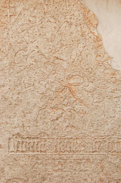 Yıpranmış bir yüzeye oyulmuş figürler ve dekoratif oymalarla antik taş kabartmaları yakın plan. Tarihi doku erozyonu, yaşı ve zanaatı gösteriyor, tarih, arkeoloji, miras ve zaman kavramları için uygun.