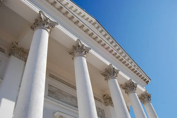 Açık mavi gökyüzüne karşı klasik beyaz sütunların düşük açılı görüntüsü. İstikrar, güç, otorite, gelenek, hukuk ve kurumsal güç kavramı. Kopyalama alanı olan en küçük mimari arkaplan