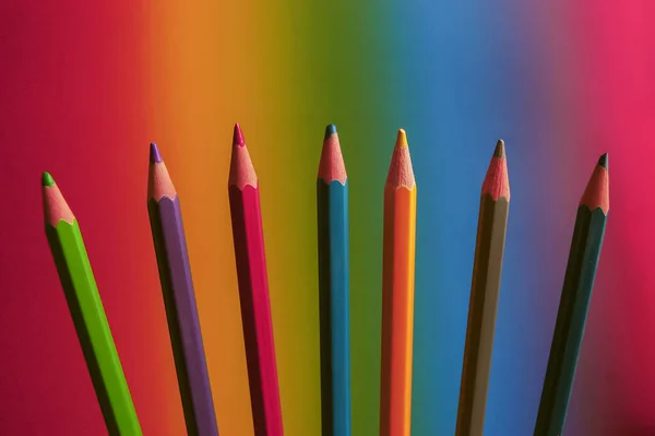Canlı bir gökkuşağı arkaplanı üzerine dizilmiş renkli kalemler. Yaratıcılık, çeşitlilik, kapsama, eğitim ve sanatsal ifade kavramı. Kopyalama alanı olan parlak minimal bileşim